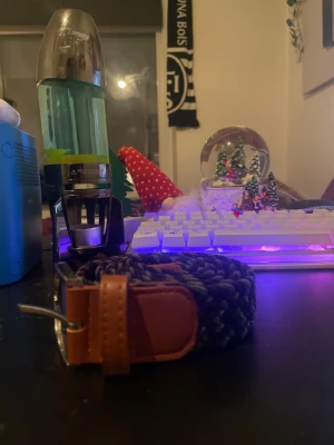 Flätbälte mörkblå  - Snyggt flätat bälte i mörkblått med detaljer i brunt skinn och ett stilrent silverfärgat spänne. Bältet har en cool struktur och passar perfekt till jeans eller chinos. Längden är 105 cm och det bruna skinnet ger en schysst kontrast mot det mörkblå tyget.