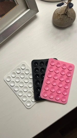 Självhäftande mobilkuddar – 3-pack - Säljer tre flexibla silikonplattor med små sugkoppar. Perfekta för att fästa mobilen på släta ytor (t.ex. spegel, kakel, skrivbord) eller för extra grepp på skal och andra prylar.