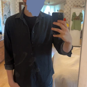 Svart slim fit skjorta Calvin Klein - Svart skjorta från Calvin Klein med diskret vitt prickigt mönster. Slim fit-modell med stretch för extra komfort. Klassisk krage, knäppning framtill och långa ärmar som kan vikas upp. Perfekt för en clean och stilren look.