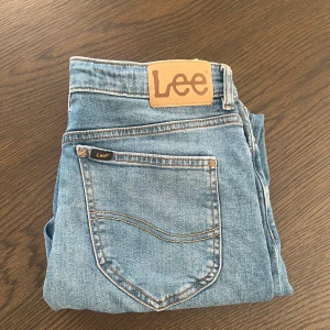 Lee Daren ljusblå jeans - Säljer ett par klassiska Lee Daren jeans i ljusblå tvätt. Jeansen har raka ben, fem fickor och snygga kontrastsömmar. Tillverkade i slitstarkt bomullsjeansmaterial med Lee-logga på bakfickan och läderpatch i midjan. Barn storlek 14-15Y storlek med resår, aldrig andvänt