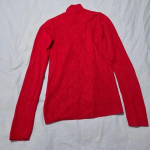 Röd Ribbstickad Polo-Tröja NA-KD Strl M/ Varm Viscose-Blend - Läcker Röd Ribbstickad Tröja från NA-KD (Polo Knitted Sweater)  En underbart mjuk och varm polotröja i en härlig, intensiv röd färg som passar perfekt under hösten och vintern, eller som ett statement-plagg.  Tröjan har en snygg ribbstickad textur och en mjuk polokrage/mock neck som värmer. Den är tillverkad i en bekväm viskosblandning som känns len mot huden.