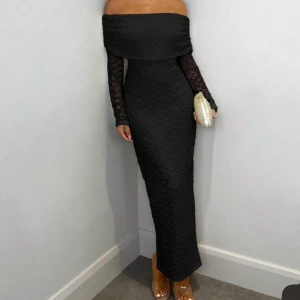 Svart långklänning med struktur - Svart långklänning med figurnära passform och diskret struktur i tyget. Klänningen har långa ärmar i genombruten spets och en slits bak för extra rörelsefrihet. Perfekt för dig som vill ha en elegant och stilren look.