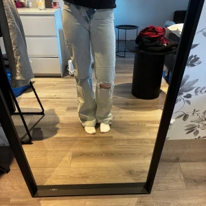 Ljusblåa jeans - Snygga ljusblå jeans från Bikbok med hög midja. Jeansen har slitna detaljer på båda benen och klassisk knappgylf. Perfekta för en avslappnad och trendig look. Jätte sköna och fina till en ljus topp på sommaren☀️har tyvärr blivit försmåa i midjan på mig🙃