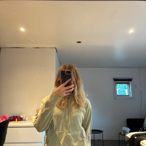 Levi's hoodie - Snygg ljusgrön hoodie från Levi's i storlek XS. Klassisk modell med huva, snörning och magficka. Tillverkad i mjuk bomull, perfekt för chill dagar. Liten röd Levi's-logga på bröstet ger en clean look. Tyvärr ett litet märke på fickan, och sömmar längst ner på ärmen ser ut att vela lossna, även lappen. Säljer även matchande T-shirt!