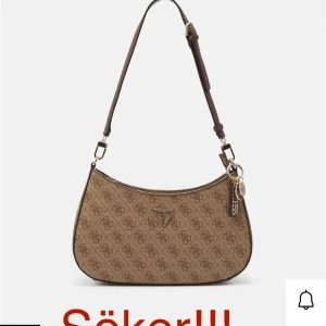 Brun axelväska från Guess - Hejsan! Min mamma söker efter denna guess noelle lattw handbäskan! Skriv till mig om ni har en ni vill sälja