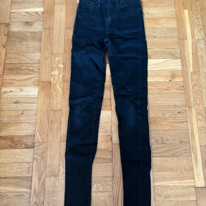 Levi's Mile High Super Skinny jeans svart - Svarta Levi's Mile High Super Skinny jeans med hög midja och supertight passform. Klassisk femficksmodell med Levi's-logga på bakfickan och patch bak i midjan. Snygga och stilrena jeans i stretchigt material som sitter som en andra hud.