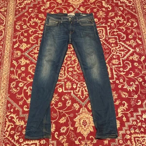 Replay Hyperflex  - Säljer ett par Replay Hyperflex jeans i klassisk blå tvätt med snygga slitningar. Jeansen har raka ben, fem fickor och kontrastsömmar. Märkespatch i läder baktill. Stretchigt material för extra komfort och rörelsefrihet.