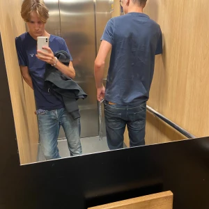 Mörkblå t-shirt från Tommy Hilfiger - Snygg mörkblå t-shirt från Tommy Hilfiger med diskret logga på bröstet. Klassisk rund hals och korta ärmar, perfekt passform som sitter skönt. Materialet är mjuk bomull som andas bra. Enkel och stilren design som funkar till jeans eller shorts.