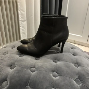 Svarta stövletter i skinn med klack - Snygga svarta stövletter i äkta skinn med spetsig tå och smal klack. Klassisk och stilren modell som passar perfekt till både jeans och klänning. Dragkedja på insidan för enkel på- och avtagning.
