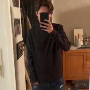 Mörkgrå sweatshirt från Tiger of Sweden - Snygg mörkgrå sweatshirt från Tiger of Sweden i storlek M. Tröjan har rund hals, långa ärmar och en stilren design utan mönster. Materialet är mjuk bomull blandat med polyester, vilket gör den skön att bära. Perfekt för dig som gillar minimalistisk stil.