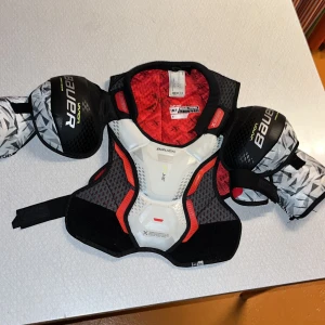 Vapor 3X Shoulder Pad INT Medium - Bauer Vapor 3X axelskydd i storlek INT Medium, passar bröstvidd 71-81 cm. Modern design med bra skydd och komfort, perfekt för hockeyspelare. Skicket är mycket gott, inga synliga defekter eller slitage. .