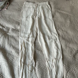 Beiga linnebyxor med snörning XS - Luftiga beiga linnebyxor i storlek XS med resår och snörning i midjan. Byxorna har raka ben och sidfickor, perfekta för varma dagar. Materialet är krinklat linne som ger en avslappnad vibe. Ordinarie 399kr, pris 100kr