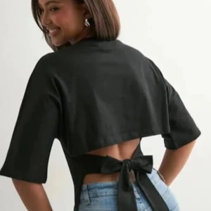 Svart croppad topp med knyt i ryggen - Snygg svart topp ifrån nelly med knytning i ryggen. Toppen är i storlek M men passar asbra för mig som ofta bär xs/s, pris går att diskutera🫰🫰🫰