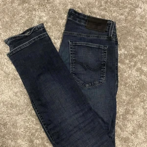 Mörkblå jeans från Jack and Jones - Snygga mörkblå jeans från Jack and Jones  med klassisk femficksdesign och diskret broderad bakficka. Jeansen har en rak passform och är tillverkade i mjukt denimtyg som sitter skönt hela dagen.