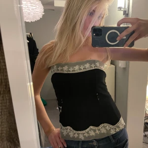 Svart tubtopp/korsett  - Är en pytte liten defekt på broderiet men syns knappt, syns ej på bild men i vissa ljus om man tittar noga! Syns ej när man har den på och väldigt litet. 