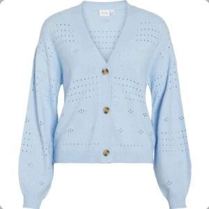 Ljusblå kofta från Vila med knappar - Superfin ljusblå kofta från Vila med v-ringning och stora bruna knappar. Koftan har ett stickat hålmönster, ribbade muddar och lång ärm. Perfekt att slänga över en t-shirt för en chill look. Aldrig använd, nypris 500kr 