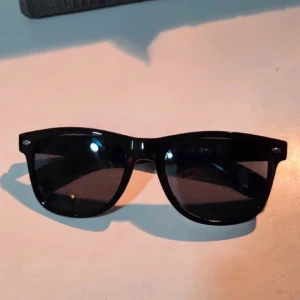 Svarta hjärtformade effektglasögon - Coola svarta glasögon med klassisk wayfarer-form som skapar ett hjärta i regnbågens färger när du tittar på ljus. Perfekta för att ge en unik twist på din stil och för att få magiska effekter på fester eller konserter.