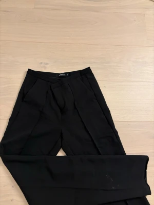 Svarta kostymbyxor  - Säljer ett par svarta kostymbyxor från Gina Tricot. Lite smutsiga ned till men kan tvätta dem. Lite högre i midjan och utsvängda ner till. 