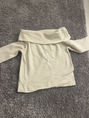 Off shoulder tröja från H&M, vit - Säljer en ribbad off shoulder tröja från H&M i vit färg. Tröjan har långa ärmar och en bred, nedvikt krage som ger en snygg och avslappnad look. Perfekt att styla med jeans eller kjol för en trendig outfit. Det står L på tröjan men passar S! 🙌
