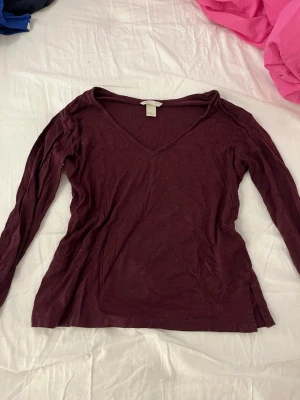 Vinröd långärmad topp H&M Basic XS - Vinröd långärmad topp från H&M Basic i mjuk bomull. Toppen har v-ringning och en enkel, klassisk design som passar till det mesta. Perfekt att styla med jeans eller kjol för en avslappnad look.