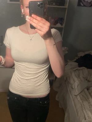 Vit tight t-shirt med knyt i ryggen - Snygg vit t-shirt med tight passform och korta ärmar. T-shirten har en unik detalj med knytband i ryggen som ger en cool twist. Perfekt att styla med jeans eller kjol för en trendig look.