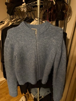 Blå stickad ziptröja från Weekday - Mysig blå stickad tröja från Weekday med dragkedja framtill. Tröjan har en rak passform, ribbad krage och långa ärmar. Perfekt för lager-på-lager och chill vardagsstil.