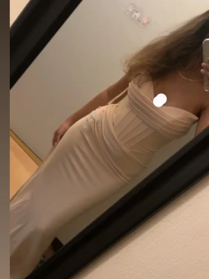 Champagnefärgad långklänning med inbyggd bh - Supersnygg axelbandslös långklänning  i champagnefärg med en slits på höger ben. Perfekt för lärrarmiddag/bal/festklänning strl xs men passar s. Den är använd 1 gång så den är i väldigt bra skick!. 