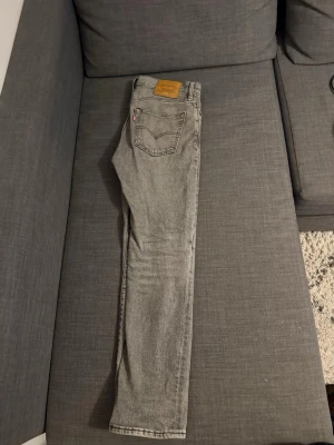 Levi's 511 grå jeans W31 L30 - Säljer ett par grå Levi's 511 jeans i klassisk femficksmodell. Jeansen har en slim passform och raka ben, med snyggt tvättad finish och klassisk läderpatch bak. Perfekta för dig som gillar stilrena och bekväma jeans. Är 170-175 och väger 65kg ungefär och byxorna sitter fantastiskt bra! Köpt för 1150kr