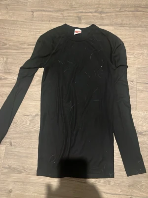 Svart långärmad topp från Newbody - En svart, enkel och stilren långärmad topp från Newbody. Modellen är figurnära med rund halsringning och tillverkad i ett mjukt och stretchigt material som passar perfekt till lager-på-lager eller som basplagg.