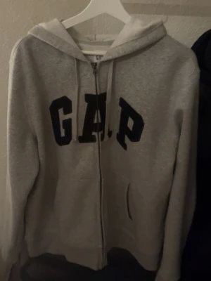 GAP ZipUp Hoodie - Säljer en grå Gap zipup hoodie som jag använt ett fåtal gånger men är i nästan nyskick o den är i storlek M och om ni har några frågor tveka verkligen inte på att ställa dom!☺️ 💯 