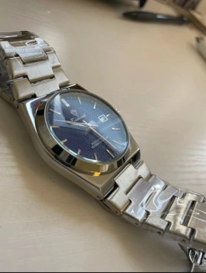 herrklocka 41mm blå urtavla rostfritt stål - Snygg herrklocka med blå urtavla och subtilt rutmönster. Klockan har en rund form, datumvisning och silverfärgat armband i metall. Perfekt accessoar för dig som gillar klassisk design.