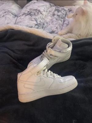 Nike Air Force 1 vita high sneakers - Klassiska vita Nike Air Force 1 high sneakers med snörning och kardborreband runt ankeln. Knappt använda inget fel på dom och tvättas innan vid köp 