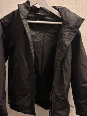 Svart regnjacka från Everest barn 134/140 - Säljer en svart regnjacka från Everest med huva och dragkedja framtill. 