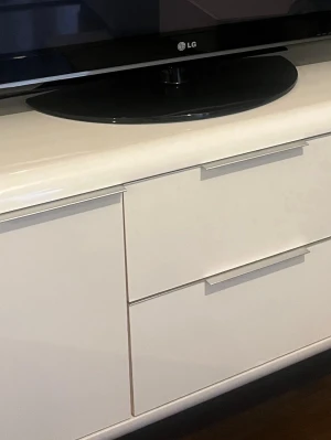 Vit tv-bänk med lådor - Snygg vit tv-bänk i modern design med tre lådor och stilrena handtag. Tillverkad i slät, blankt material som ger ett fräscht intryck. Perfekt för förvaring av elektronik, spel eller andra prylar i vardagsrummet.