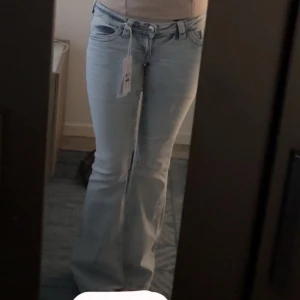 Bootcut ljusblå jeans med rosa broderi - Snygga ljusblå bootcut jeans från Gina tricot med rosa broderade detaljer på bakfickan. Jeansen har klassisk femficksdesign, låg midja. Perfekt passform med utsvängda ben för en cool vibe.