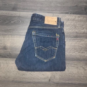 Replay Waitom jeans  - Säljer ett par mörkblå jeans från Replay med klassisk femficksdesign och snygga kontrastsömmar. Jeansen har rak passform. OBS storlekslappen är borta men jag bedömer storleken till W34 L32 men utgå från måtten för att vara säker midja 43cm, längd 100cm. JAG SKICKAR EJ FLER BILDER NÄR JAG BÄR JEANSEN! för storleksguide hänvisar jag till måtten och för bättre inblick i passformen rekommenderar jag att googla på modellnamnet :) s3