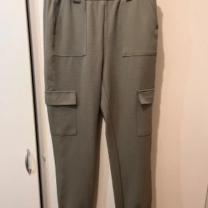 Cargo byxor strl M - Cargo byxor i strl M. Köpt från Gina Tricot.  Stretchigt material, lite högmidjade.  Fickor på sidan.  Mycket fint skick, endast använda en gång. Material: polyester och elastan