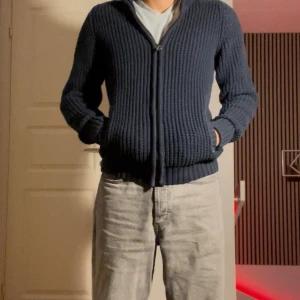 Marinblå stickad kofta från H&M L.O.G.G. - Säljer en marinblå stickad kofta från H&M L.O.G.G. i storlek S. Koftan har grov ribbad struktur, dragkedja framtill och två fickor. Perfekt för kyliga dagar och enkel att matcha med jeans eller andra plagg.