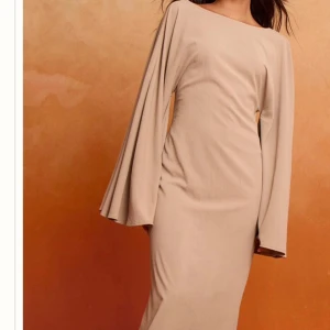 Beige heltäckande klänning - OANVÄND MED PRISLAPP KVAR, Elegant beige klänning, design som passar både till vardags och fest. Skön passform och mjukt material gör den bekväm att bära hela dagen. Perfekt för dig som gillar stilrent och hållbart mode.
