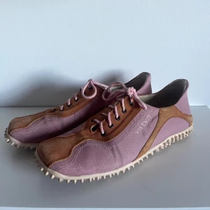 Viventy sneakers i rosa och brunt - Unika sneakers från Viventy i en snygg kombo av rosa textil och orangea bruna mockadetaljer. Skorna har snörning och en cool, mönstrad sula med gummidubbar för extra grepp. Perfekta för dig som vill sticka ut med en sportig och trendig look.