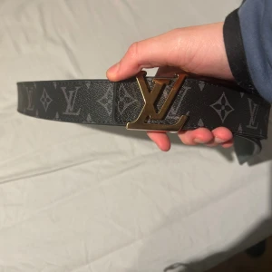 Svart märkes bälte guldig logga - Snyggt svart märkes bälte med guldig logga.