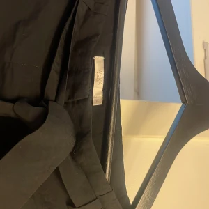 Svarta kostymbyxor med knyt från Wera - Svarta kostymbyxor från Wera i storlek 38. Byxorna har ett snyggt knytband i midjan och raka ben. De är tillverkade i ett mjukt tyg som känns skönt mot huden och har en klassisk look med fickor både fram och bak.