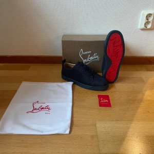 Christian Louboutin mörk blå sneakers - Snygga svarta sneakers från Christian Louboutin med klassisk röd sula och diskret logga undertill. Skorna har rund tå, snörning och är tillverkade i mocka med detaljer i skinn. Perfekta för dig som vill sticka ut med exklusiv stil och ikoniska detaljer. Pris kan diskuteras👍🏼