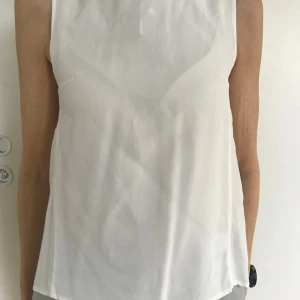 Vit topp Sthlm stl 34 Ny - Jättefin vit topp från MQ Stockh lm med fin detalj i bak. Stl 34. 100% viscose Ny Nypris: 399:-