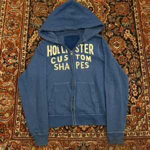 Vintage hollister hoodie - Riktigt fet vintage Hollister hoodie! Dessa har blivit extremt eftertraktade senaste så därav priset! Bra skick inga konstigheter!  Mått: Bredd: 47cm Längd: 60cm