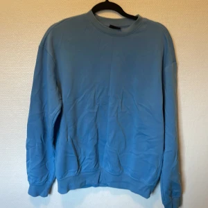 Blå sweatshirt från H&M relaxed fit - Blå sweatshirt från H&M i relaxed fit. Tröjan har rund hals, ribbade muddar vid ärmslut och nederkant samt långärmad design. Perfekt för chill dagar och enkel att matcha med jeans eller mjukisbyxor.