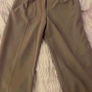 Beige kostymbyxor med raka ben - Snygga beige kostymbyxor med raka ben och minimalistisk design. Byxorna har två diskreta bakfickor och en klassisk midja. Perfekta för en clean och stilren look. Materialet känns mjukt och har en lätt stretch.