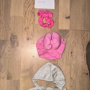 2 baby-mössor, rosa rosett & grå knyt Set med babyaccessoarer - Säljer två söta baby-mössor: en rosa mössa med stor rosett framtill och en enkel grå mössa med knytband under hakan. Perfekt för små barn 0-3 månader. Båda är mjuka och bekväma, tillverkade i bomull.Ett set med tre söta accessoarer för bebisar. Inkluderar en grå knythätta, ett rosa pannband med rosett och en rosa hårklämma. Turban mössa pannband hårband 