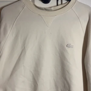 Lacoste Sweatshirt - Säljer en stilren vit sweatshirt från Lacoste. Perfekt för en clean och avslappnad look. Först till kvarn, passa på!🚀