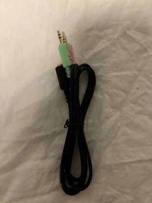 Svart ljudkabel med 3,5mm kontakter - En svart ljudkabel med två 3,5mm kontakter, en grön och en rosa, samt en svart hona. Perfekt för att koppla ihop headset eller mikrofon till dator eller annan elektronik. Kabeln är gjord av plast och metall och är smidig att ta med sig.